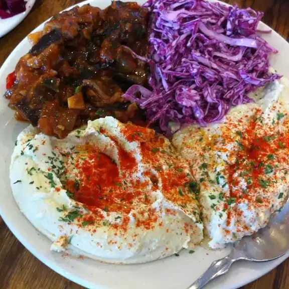 Mediterranean appetizer platter with creamy hummus, shredded red cabbage salad, and seasoned eggplant dip