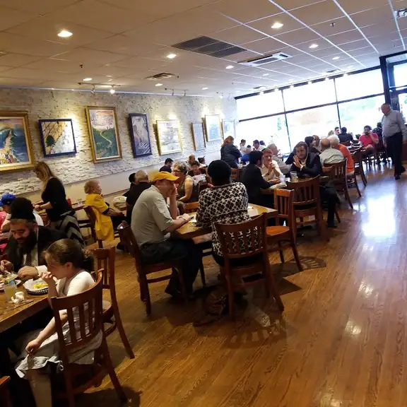 Warmly lit interior dining room of Taboun Grill restaurant filled with guests eating at tables