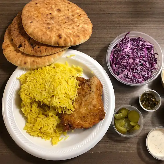 Taboun Grill dinner meal with seasoned yellow rice, roasted chicken, flat pita bread, and cabbage salad