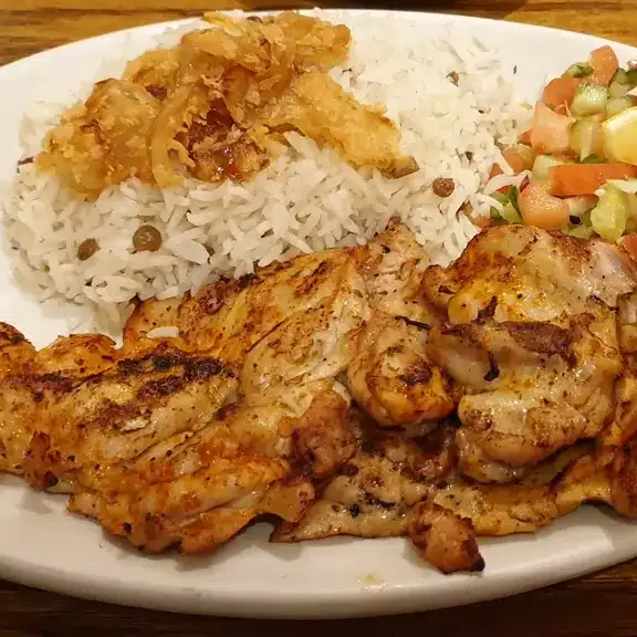 Grilled chicken pieces served with fluffy white rice topped with fried onions and side salad